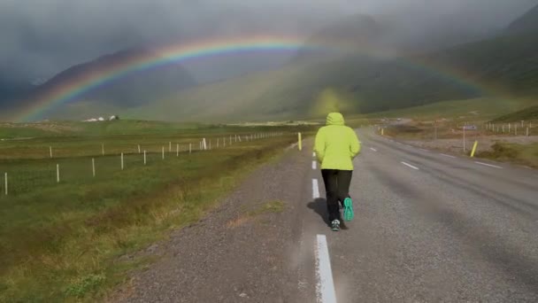 Una chica va al arco iris a lo largo del camino — Vídeos de Stock