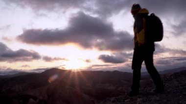 İnsan dağa tırmandıktan sonra muzaffer bir şekilde kollarını kaldırır.