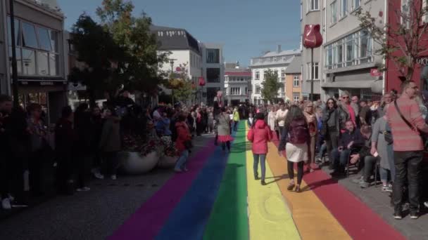 Reykjavik κεντρικό δρόμο με ουράνιο τόξο πεζοδρόμιο και τον καθεδρικό ναό στο παρασκήνιο — Αρχείο Βίντεο