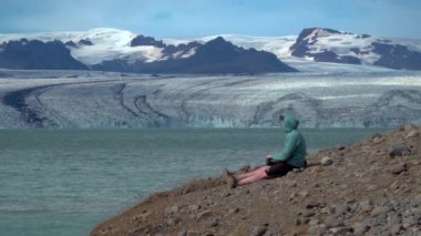 İzlanda 'daki turist Jokulsarlon Buzul Gölü' ne bakıyor