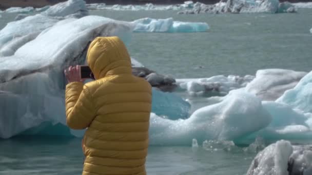 Турист в Ісландії дивиться на льодовик Йокулсарлон. — стокове відео