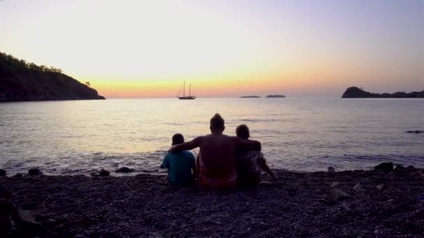 Pai com filhos junto ao mar ao amanhecer — Vídeo de Stock