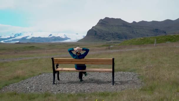 Une femme assise sur un banc admire la nature de l'Islande . — Video