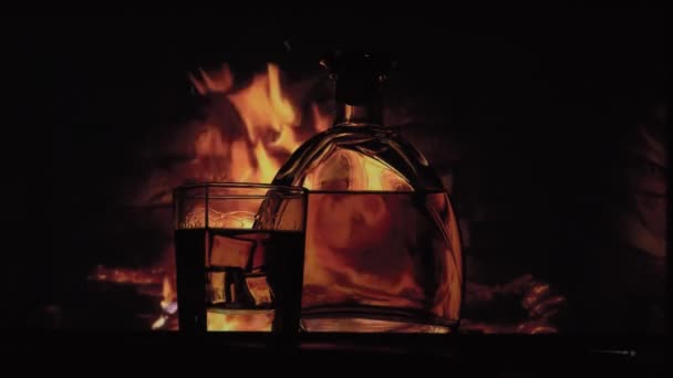 Botella y vaso de alcohol cerca de la chimenea — Vídeos de Stock