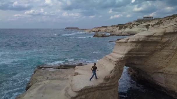 Bir kız deniz kıyısında bir kayaya tırmanıyor. — Stok video