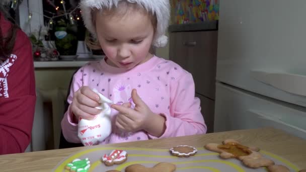 Mädchen bemalt Weihnachtsplätzchen. — Stockvideo