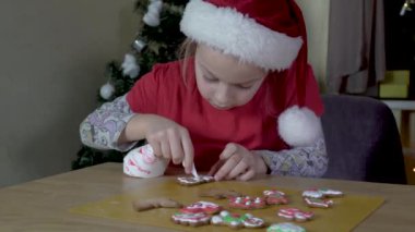 Child paints Christmas cookies.