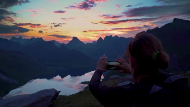ハイカーは山のピークに達し、日没の写真を撮る — ストック動画
