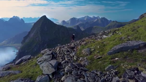 Vzdušný pohled na dívku s batohem stoupá na hřeben hory — Stock video