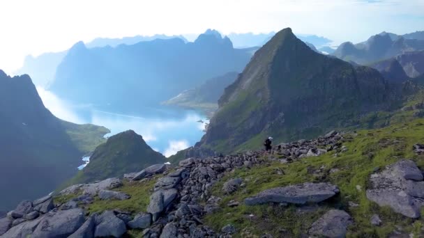 Vista aérea de chica con una mochila se levanta en una cresta de montaña — Vídeos de Stock