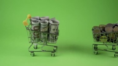 Bozuk paralı alışveriş arabası, banknotlar ve kredi kartı sürücüsü yeşil arka planda.
