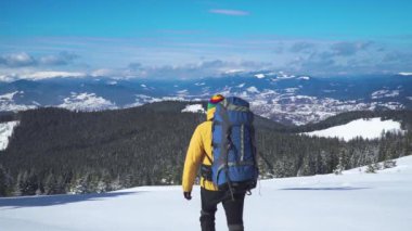 Sırt çantalı turist kar manzarasında yürüyor.