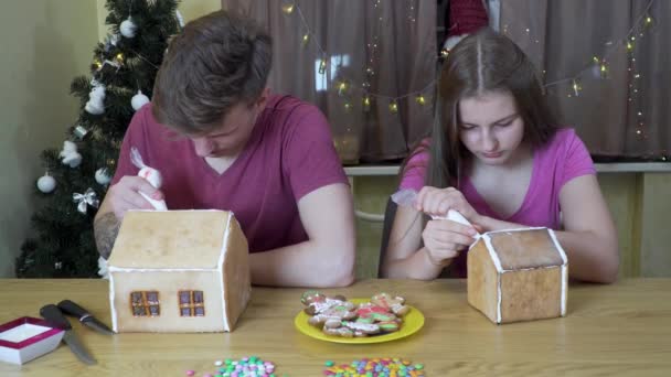 Um cara e uma menina decorar uma casa de gengibre de Natal — Vídeo de Stock