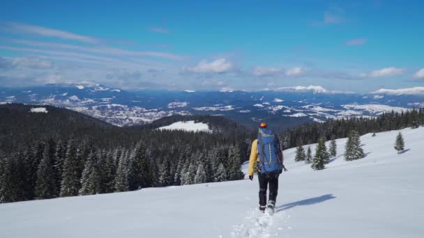 Чоловік з рюкзаком подорожує в горах взимку — стокове відео