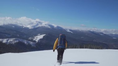 Sırt çantalı bir adam kışın dağlarda seyahat eder.