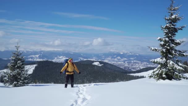 Человек с рюкзаком путешествует по горам зимой — стоковое видео