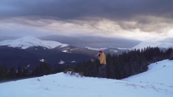 Um viajante fala ao telefone nas montanhas no inverno — Vídeo de Stock