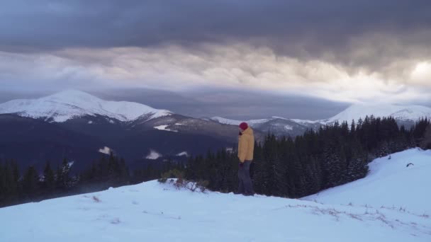 Путешественник разговаривает по телефону в горах зимой — стоковое видео