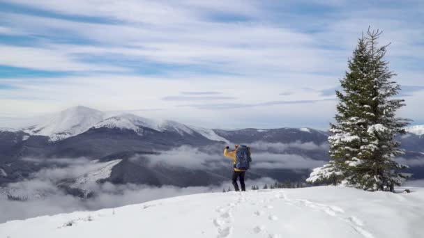 Sırt çantalı bir adam kışın dağlarda seyahat eder. — Stok video