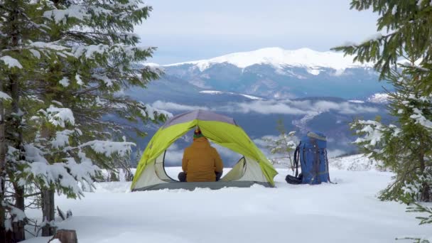 Turista relaxa em uma tenda nas montanhas no inverno — Vídeo de Stock