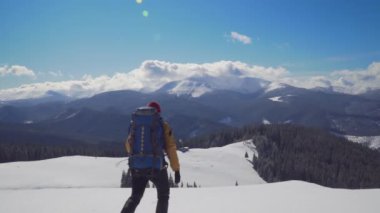 Sırt çantalı bir adam kışın dağlarda seyahat eder.