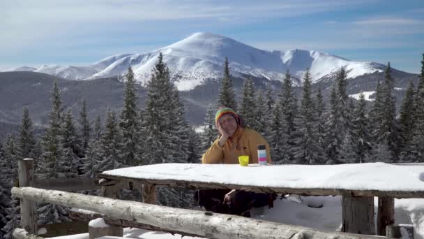 冬天，一个男人坐在山里的一张桌子旁 — 图库视频影像