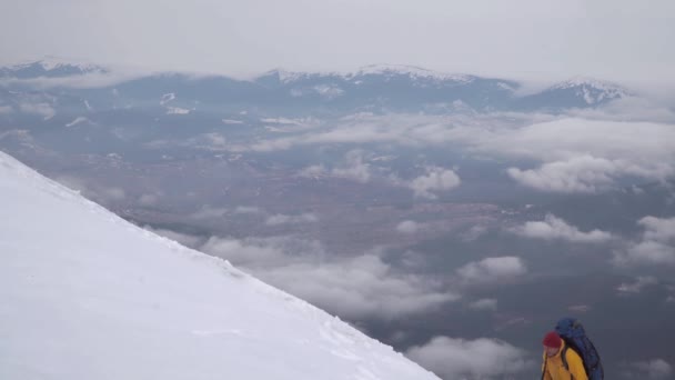 Ένας ταξιδιώτης σκαρφαλώνει στην χιονισμένη πλαγιά του βουνού — Αρχείο Βίντεο