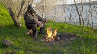 Ateşin yanında gaz maskeli bir adam.