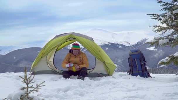 Viaggiatore vicino a una tenda in montagna in inverno — Video Stock