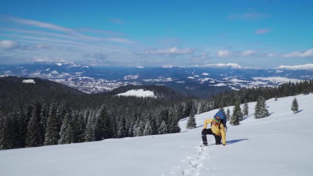 Un hombre con una mochila viaja por las montañas en invierno — Vídeos de Stock
