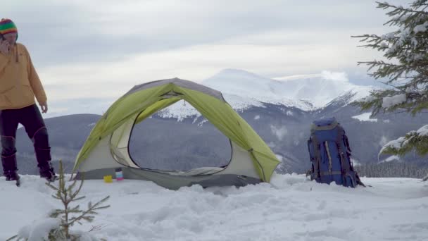 Мужчина разговаривает по телефону у палатки зимой в горах — стоковое видео