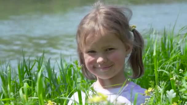 Retrato de una niña sonriente en la hierba — Vídeos de Stock