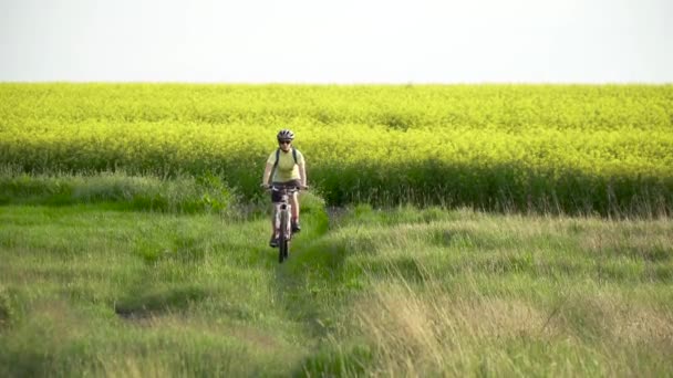 Vrouw fietser op de fiets op het platteland — Stockvideo