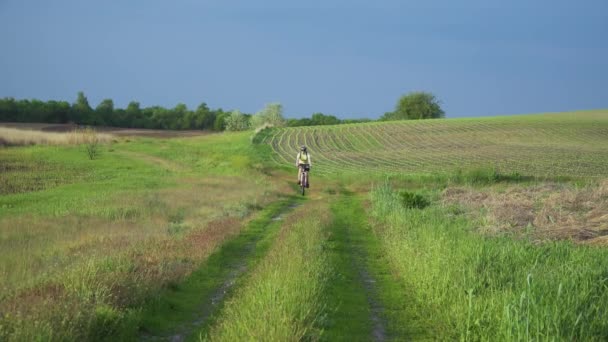 Mujer ciclista moviéndose en bicicleta en el campo — Vídeos de Stock