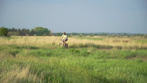 Велосипедистка переїжджає на велосипеді по сільській місцевості — стокове відео