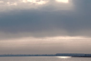 Gün batımı, alçak deniz manzarası, kara bulutlar.