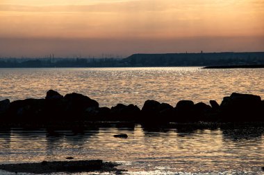 Gün batımı, alçak deniz manzarası, kara bulutlar.