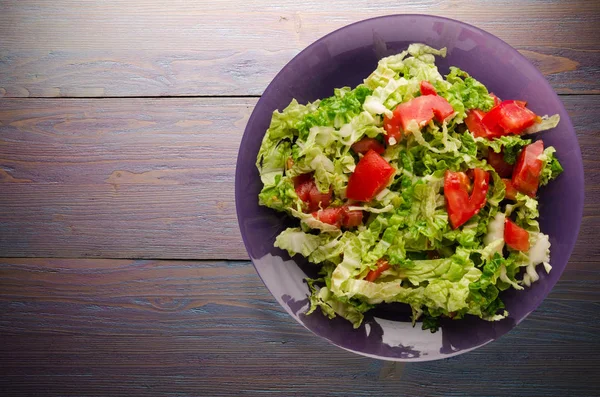  ahşap arka plan üzerinde bir tabakta lahana domates salatası