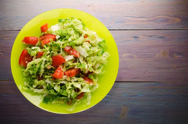  ahşap arka plan üzerinde bir tabakta lahana domates salatası