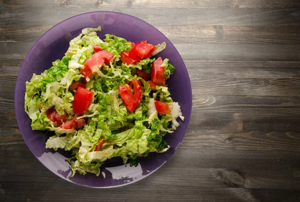  ahşap arka plan üzerinde bir tabakta lahana domates salatası