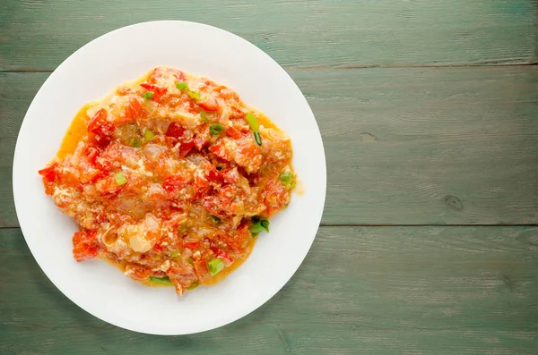 Ahşap arka plan üzerinde bir tabak içinde soğan ile haşlanmış domates.  