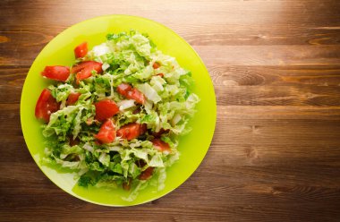  ahşap arka plan üzerinde bir tabakta lahana domates salatası