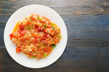 Ahşap arka plan üzerinde bir tabak içinde soğan ile haşlanmış domates 