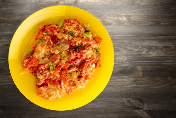 Ahşap arka plan üzerinde bir tabak içinde soğan ile haşlanmış domates 