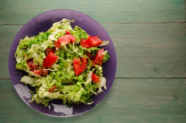  ahşap arka plan üzerinde bir tabakta lahana domates salatası