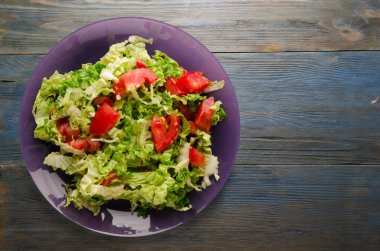  ahşap arka plan üzerinde bir tabakta lahana domates salatası