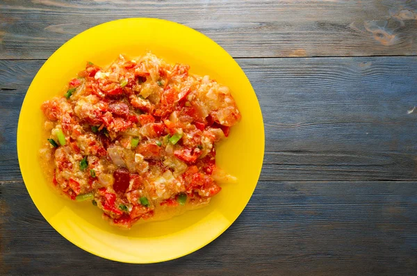Ahşap arka plan üzerinde bir tabak içinde soğan ile haşlanmış domates 