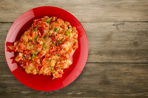 Ahşap arka plan üzerinde bir tabak içinde soğan ile haşlanmış domates. 