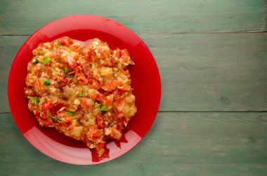 Ahşap arka plan üzerinde bir tabak içinde soğan ile haşlanmış domates 