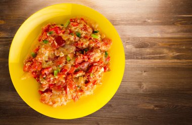 Ahşap arka plan üzerinde bir tabak içinde soğan ile haşlanmış domates 